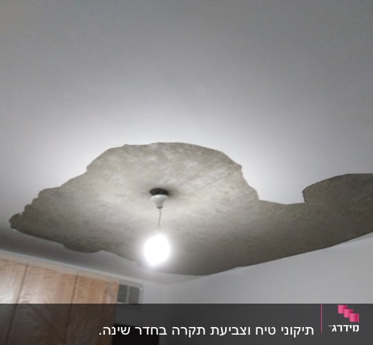 תקרה מתקלפת עם נורה תלויה במרכז